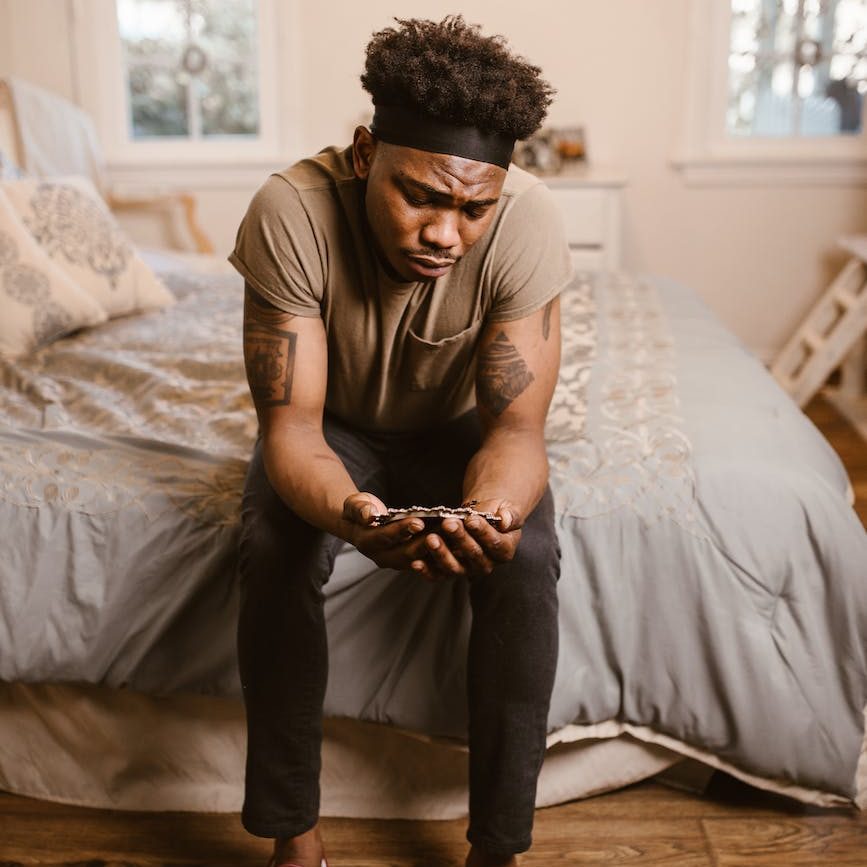 man sitting on bed while looking at picture frame